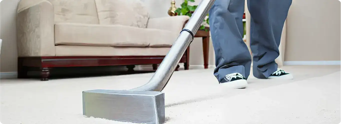 Carpet cleaning technician using a hot-water extraction wand on a light-colored carpet in a living room, Boise, ID.