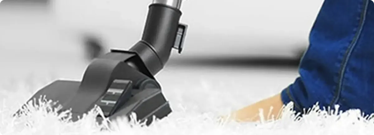 Close-up of a professional vacuuming a white carpet in Garden City.