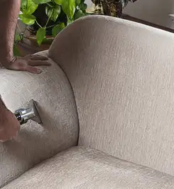 Professional upholstery cleaner deep-cleaning a fabric sofa with a handheld extraction tool and hose Boise, ID.